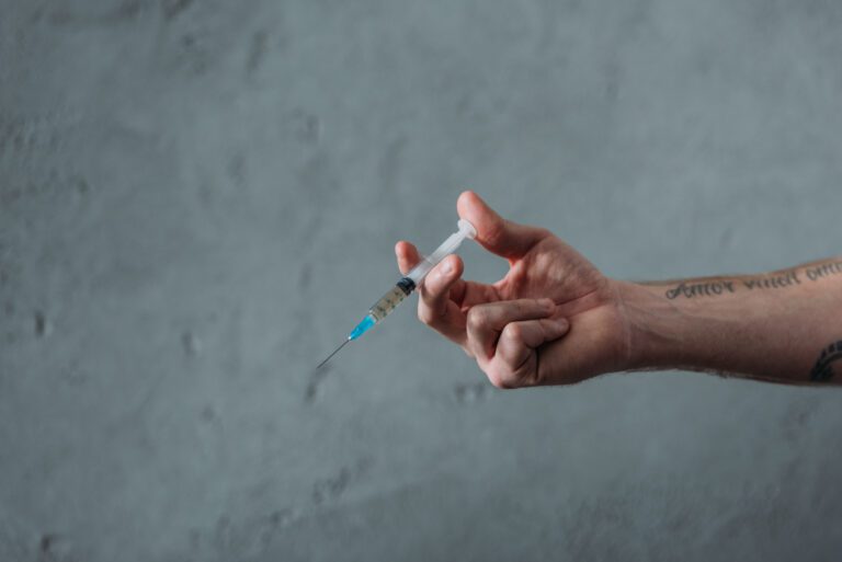 cropped shot of junkie holding heroin syringe